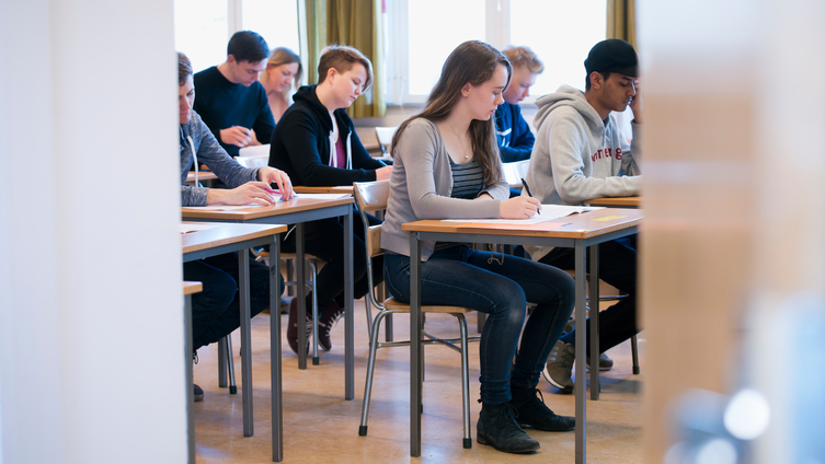 Sju ungdomar sitter och skriver högskoleprovet i en provsal. Foto: Eva Dalin