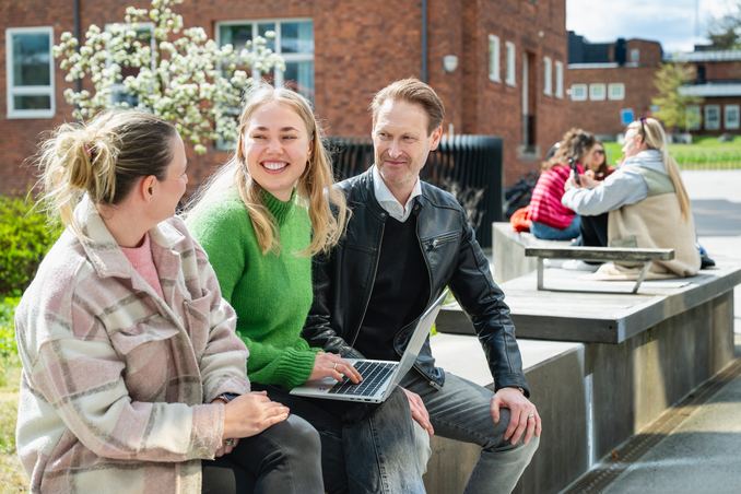 Tre studenter sitter utomhus